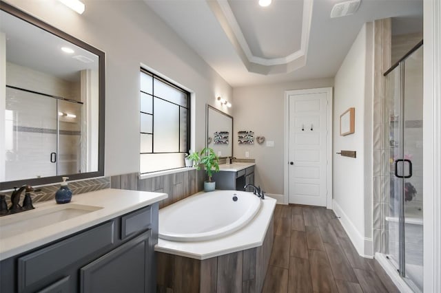 bathroom with vanity, a tray ceiling, and plus walk in shower