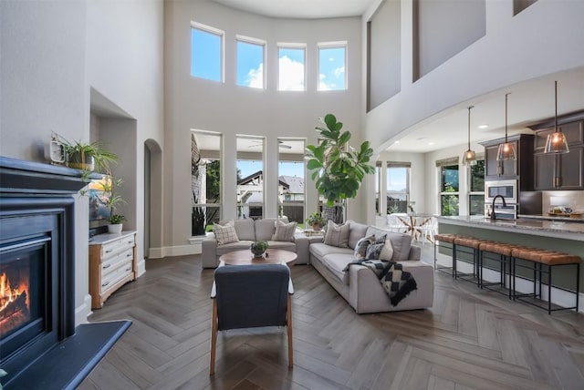 living room featuring dark parquet flooring, plenty of natural light, and sink