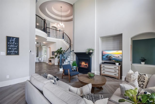 living room featuring parquet floors, a tray ceiling, a chandelier, and a high ceiling