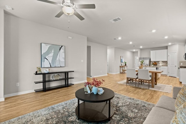 living room with ceiling fan and light hardwood / wood-style floors