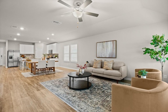 living room with ceiling fan and light wood-type flooring