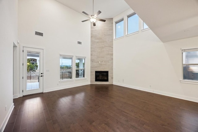 unfurnished living room with a tile fireplace, dark hardwood / wood-style floors, and ceiling fan