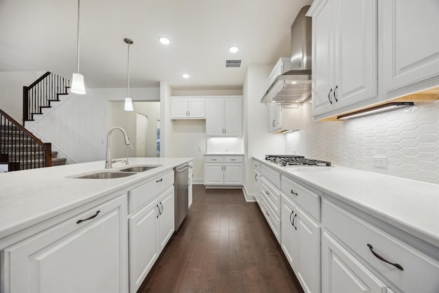 kitchen with white cabinets, decorative light fixtures, stainless steel appliances, and wall chimney exhaust hood