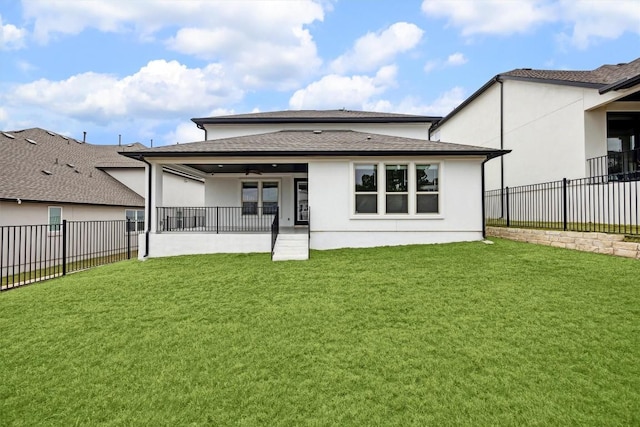 rear view of house with ceiling fan and a yard