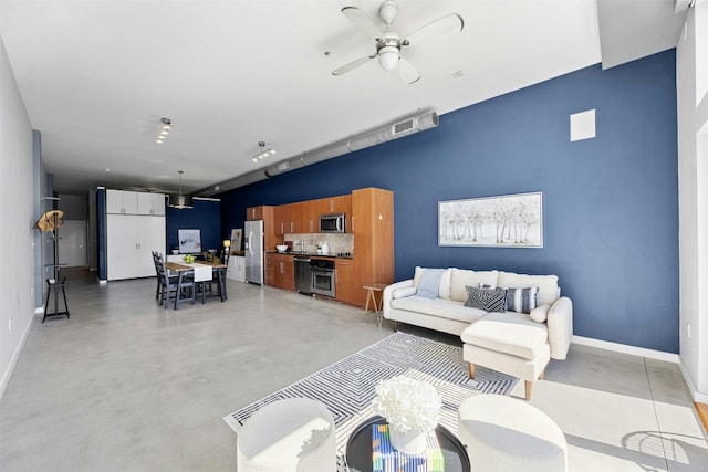 living room featuring concrete flooring, baseboards, and a ceiling fan