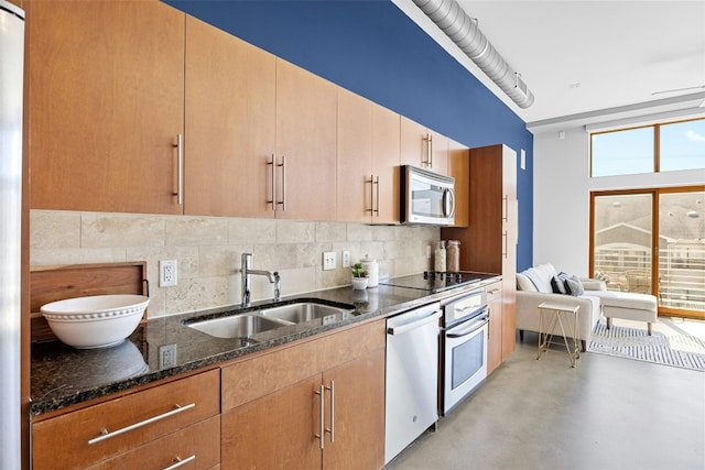 kitchen with stainless steel appliances, a sink, finished concrete flooring, backsplash, and dark stone counters