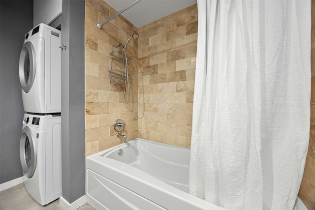 full bath featuring stacked washing maching and dryer, baseboards, and shower / bath combo with shower curtain