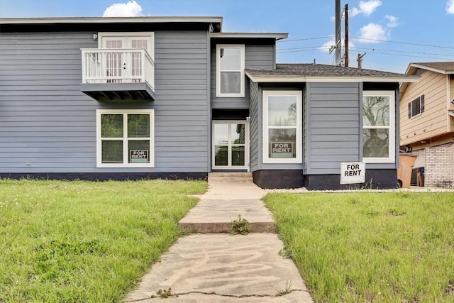 view of front of home featuring a balcony and a front yard