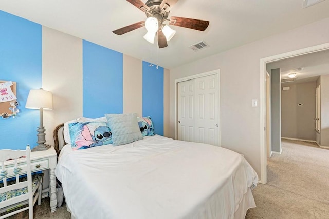 bedroom featuring light colored carpet, ceiling fan, and a closet