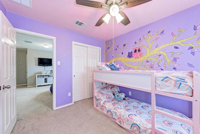 bedroom featuring light colored carpet, ceiling fan, and a closet