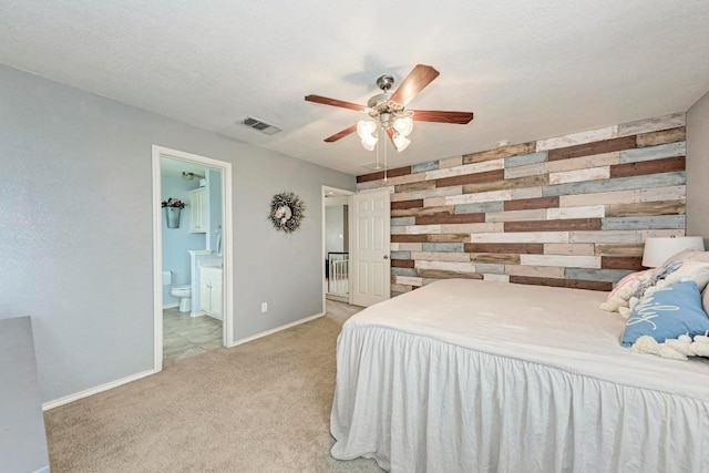 carpeted bedroom featuring connected bathroom, wooden walls, a textured ceiling, and ceiling fan