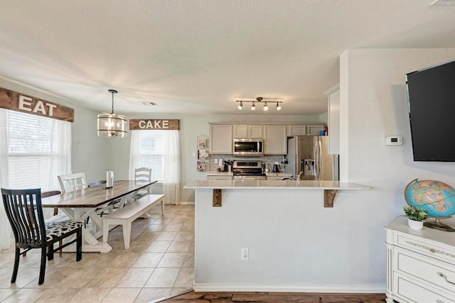 kitchen with stainless steel appliances, white cabinets, a kitchen breakfast bar, and kitchen peninsula