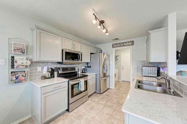 kitchen with white cabinets, stainless steel appliances, sink, and backsplash