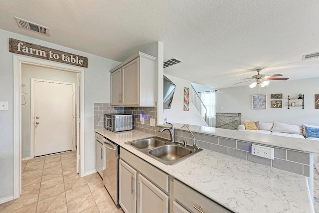 kitchen with sink, gray cabinetry, decorative backsplash, stainless steel dishwasher, and ceiling fan