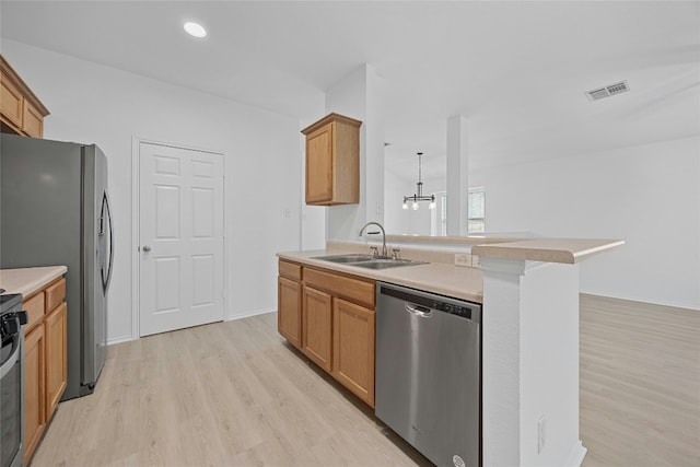 kitchen with stainless steel appliances, sink, pendant lighting, and light hardwood / wood-style floors