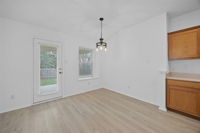 unfurnished dining area with lofted ceiling, light hardwood / wood-style flooring, and a notable chandelier