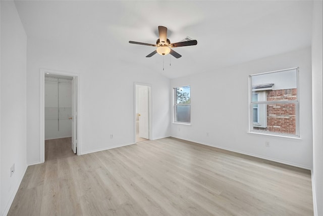 unfurnished bedroom with connected bathroom, light hardwood / wood-style flooring, a spacious closet, ceiling fan, and a closet