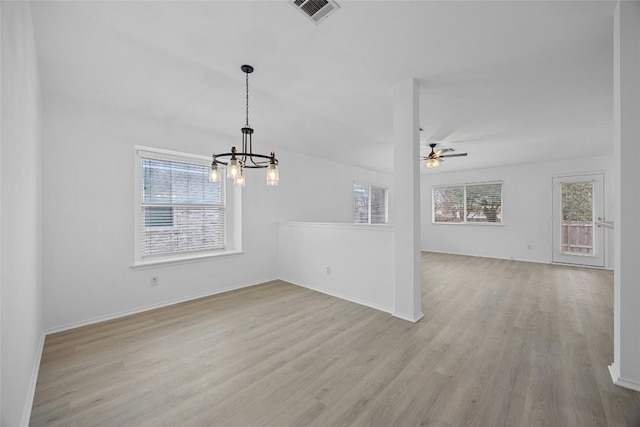 unfurnished dining area featuring plenty of natural light, ceiling fan with notable chandelier, and light wood-type flooring