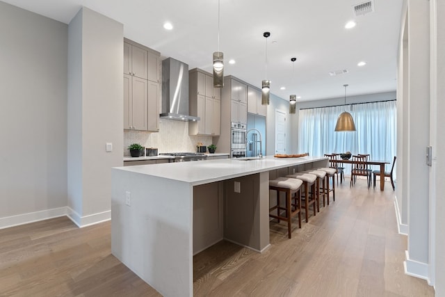 4510 Unity Cir Unit 258, Austin, TX 78731 - kitchen featuring wall chimney range hood, oven, gray cabinets, a sink, and a large island