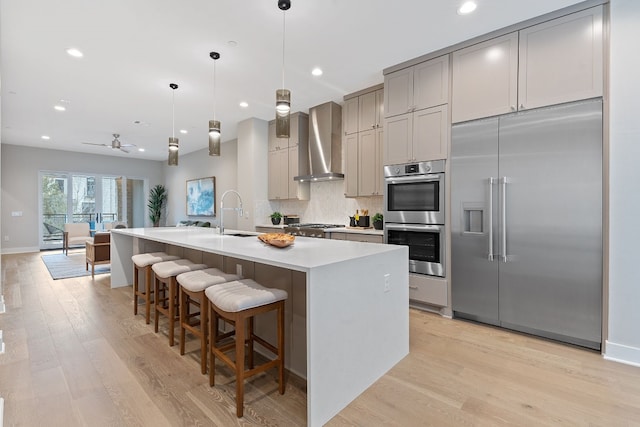 4510 Unity Cir Unit 258, Austin, TX 78731 - kitchen featuring appliances with stainless steel finishes, wall chimney range hood, gray cabinetry, light wood-style flooring, and recessed lighting