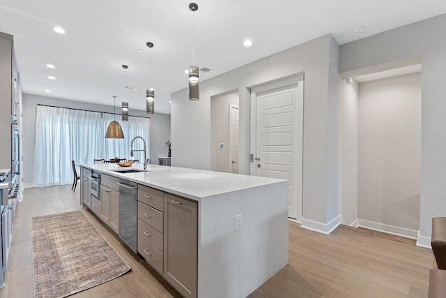 kitchen featuring sink, decorative light fixtures, light hardwood / wood-style flooring, gray cabinets, and an island with sink