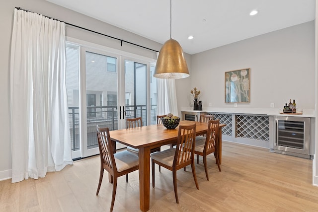 dining space with wine cooler and light hardwood / wood-style floors