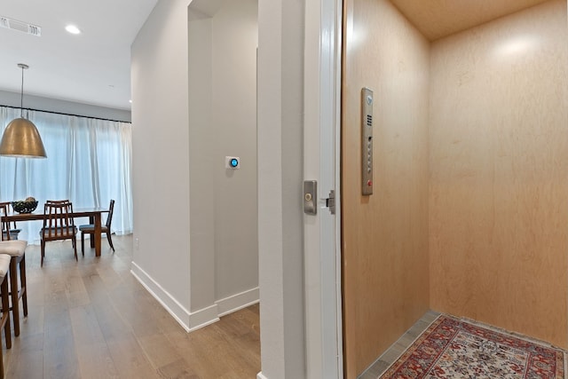 hallway with hardwood / wood-style flooring and elevator