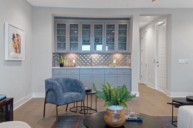 bar with tasteful backsplash, sink, and light wood-type flooring