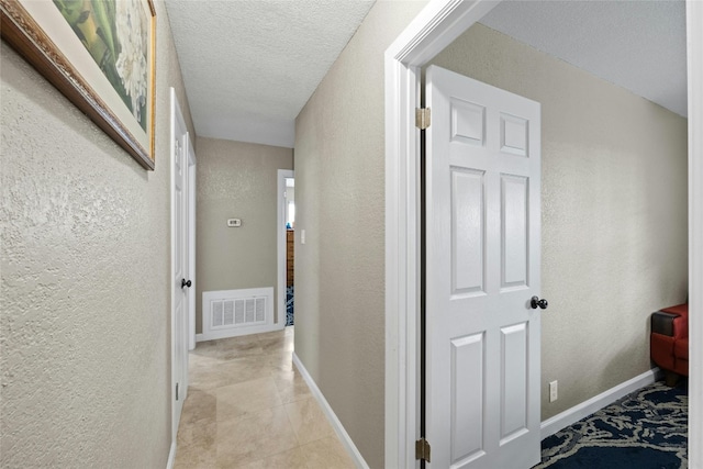 hallway with light tile patterned floors and a textured ceiling