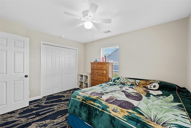 carpeted bedroom with ceiling fan, a closet, and a textured ceiling