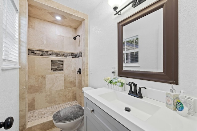 bathroom with tiled shower, vanity, and toilet