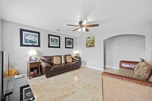 living room featuring ceiling fan and a textured ceiling