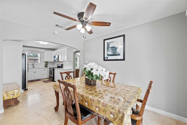 dining area featuring sink, a textured ceiling, and ceiling fan