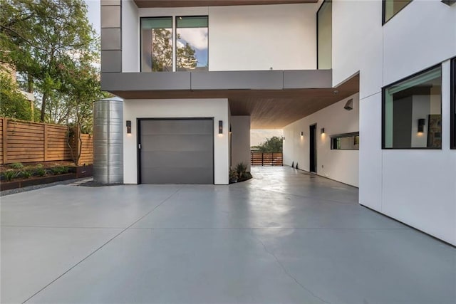 exterior space featuring concrete driveway, an attached garage, fence, and stucco siding