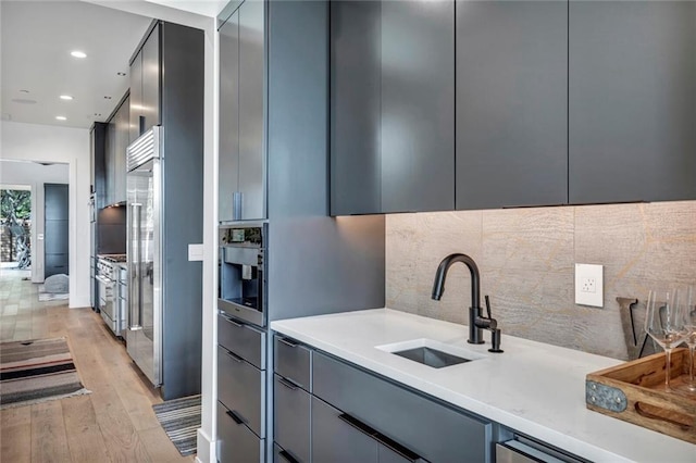 kitchen with a sink, modern cabinets, gray cabinets, and decorative backsplash