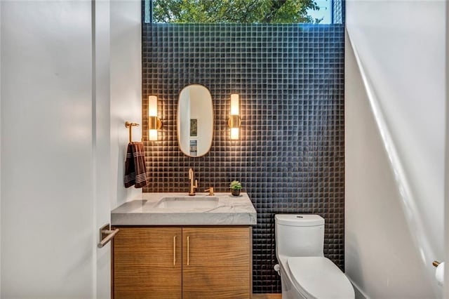 bathroom featuring plenty of natural light, toilet, vanity, and tile walls