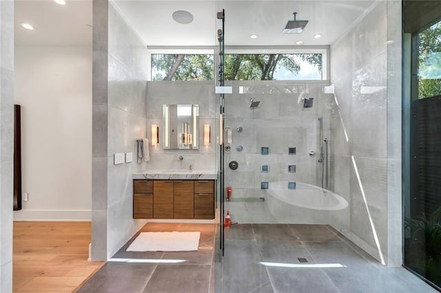 full bath featuring tile walls, a tile shower, wood finished floors, and vanity