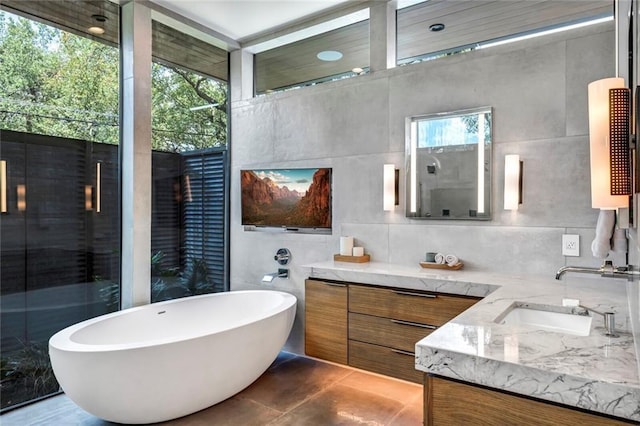 full bathroom featuring tile walls, a soaking tub, and vanity