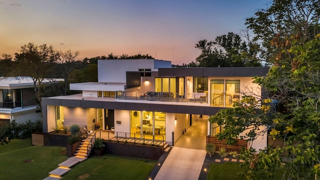 back of house with a balcony and a lawn