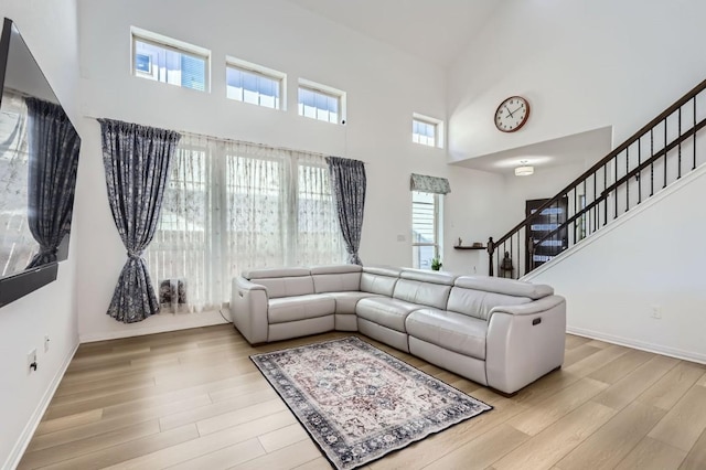 205 Audie Murphy Cir, Leander, TX 78641 - living room with a towering ceiling, light wood-style floors, stairs, and baseboards