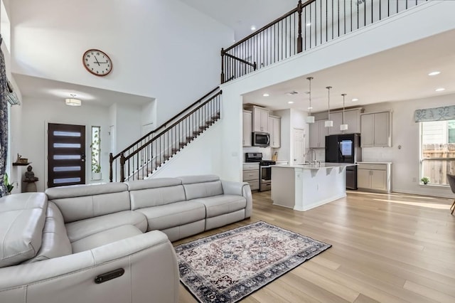 living room featuring sink, light hardwood / wood-style flooring, and a high ceiling