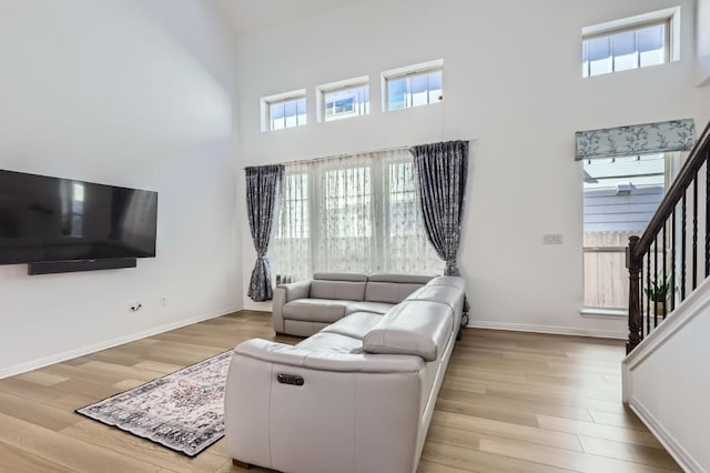 living room with a towering ceiling and light hardwood / wood-style flooring