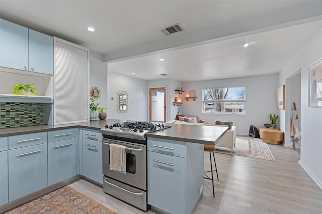 3601 Marcae Ct, Austin, TX 78704 - kitchen with gas range, a peninsula, open floor plan, light wood-style flooring, and a kitchen bar