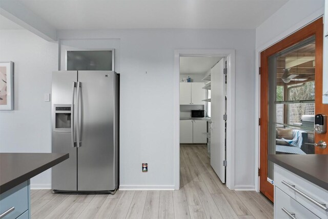 3601 Marcae Ct, Austin, TX 78704 - kitchen with stainless steel fridge with ice dispenser, dark countertops, light wood-style floors, baseboards, and white cabinets
