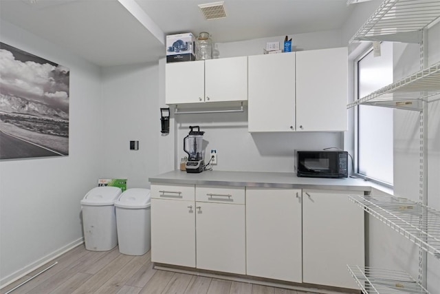 3601 Marcae Ct, Austin, TX 78704 - kitchen with black microwave, light countertops, light wood finished floors, and white cabinetry