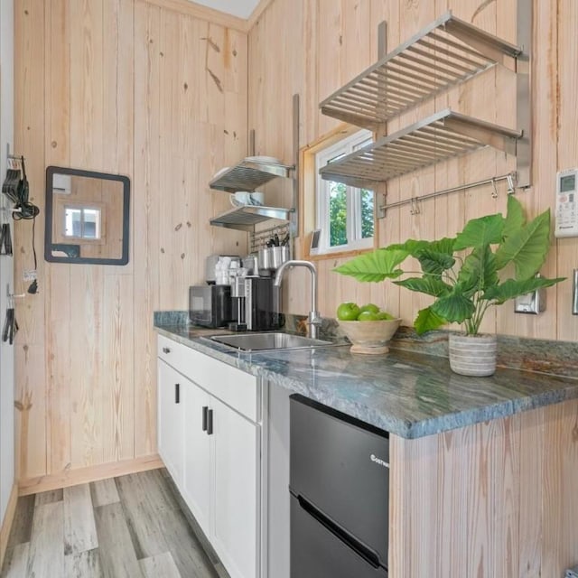 3601 Marcae Ct, Austin, TX 78704 - kitchen with wooden walls, light wood-style flooring, dark stone countertops, and white cabinets