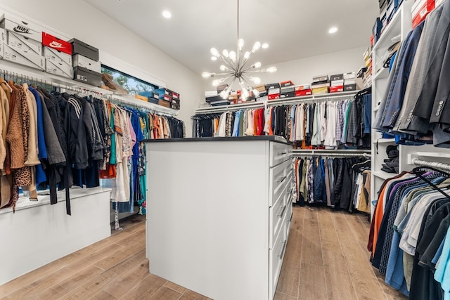 walk in closet featuring an inviting chandelier and light hardwood / wood-style flooring