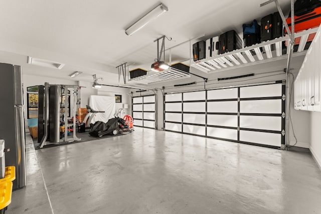 garage with a garage door opener and stainless steel fridge