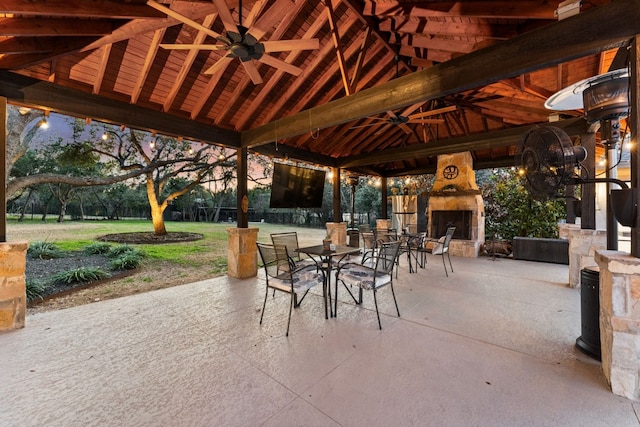 view of patio / terrace with ceiling fan, a gazebo, and an outdoor stone fireplace