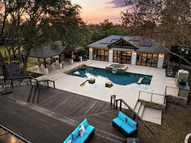 pool at dusk with an outdoor living space, an in ground hot tub, and a deck